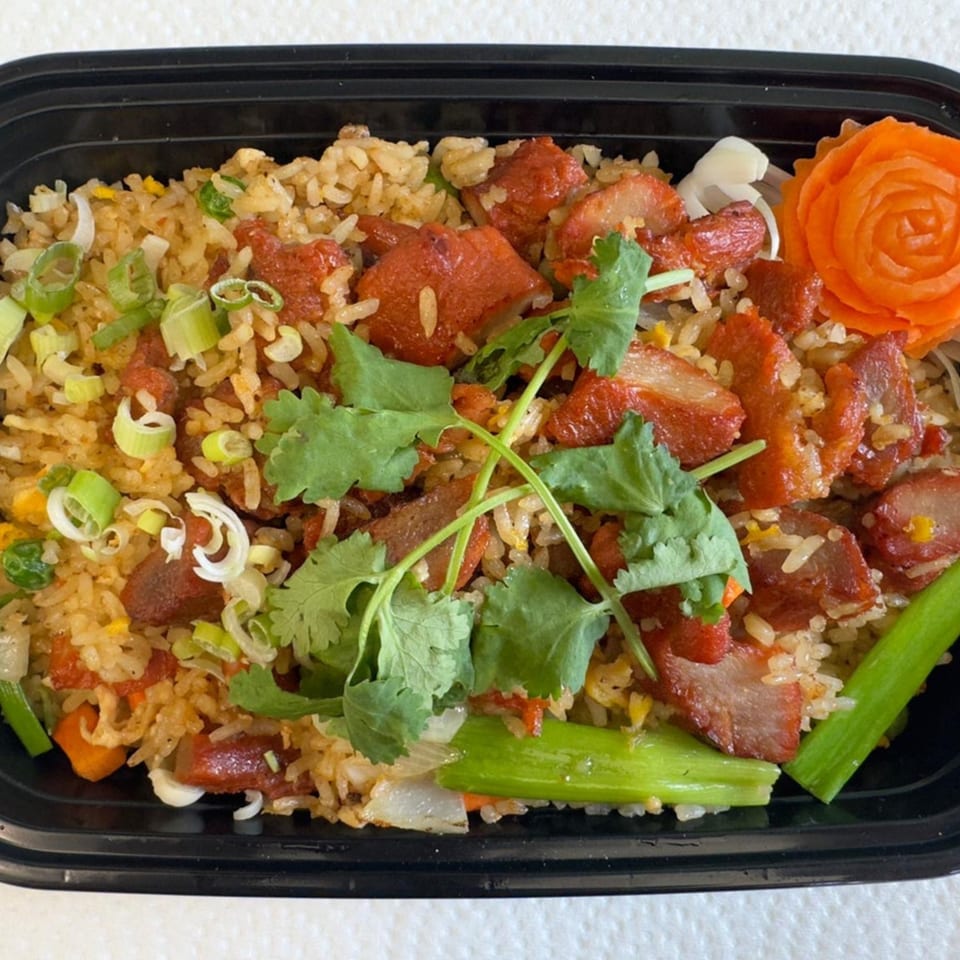 Thai Accent's fried rice with red pork, green onions, and cilantro in a black takeout container.
