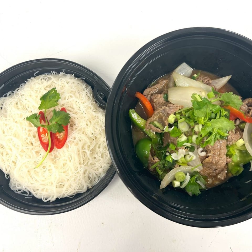 Thai beef stir-fry with onions, peppers, and cilantro, served with a side of rice vermicelli.