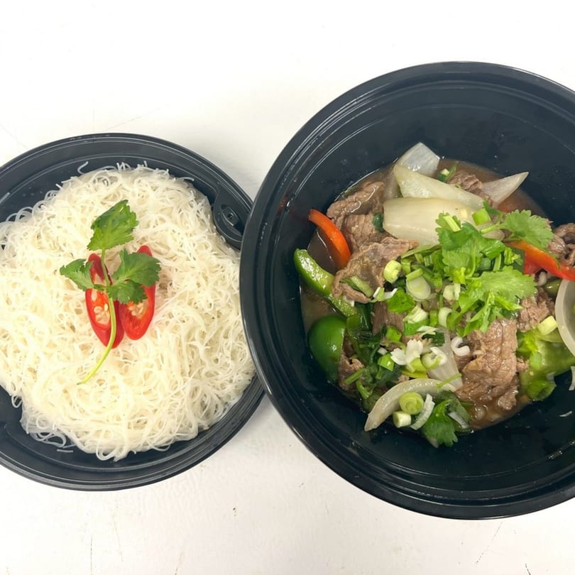 Thai beef stir-fry with onions, peppers, and cilantro, served with a side of rice vermicelli.