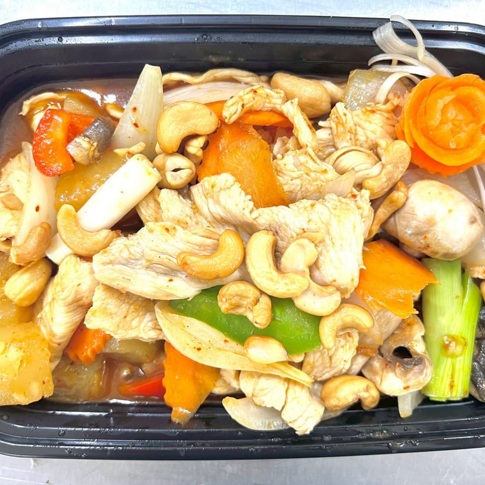Thai Accent's cashew chicken with vegetables, including carrots, onions, and green peppers, in a black container.